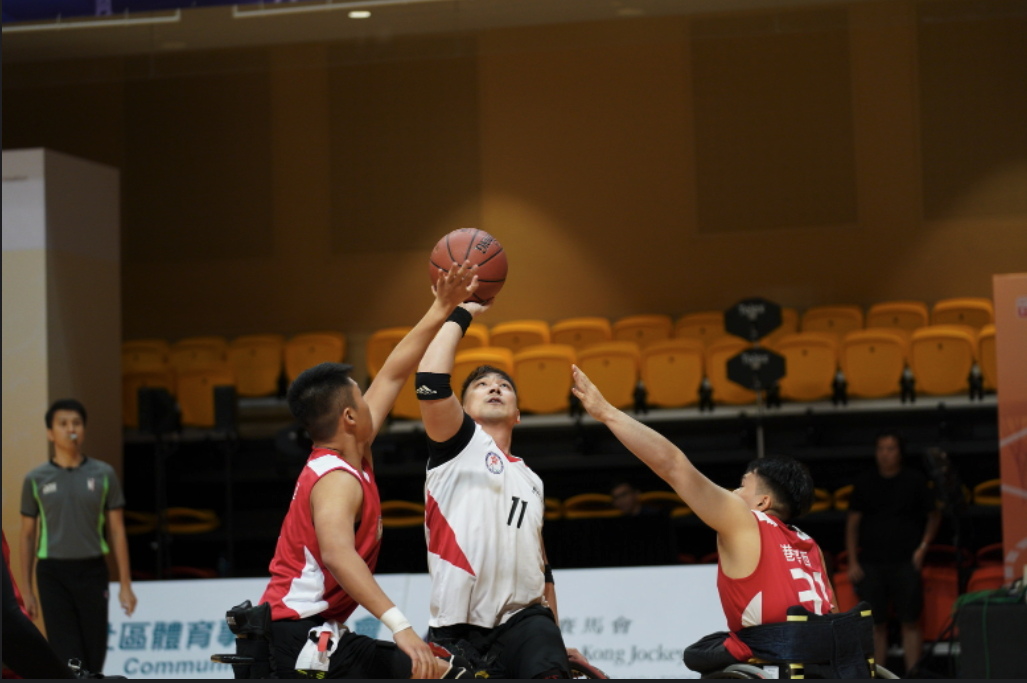 Wheelchair basketball player shooting over defenders