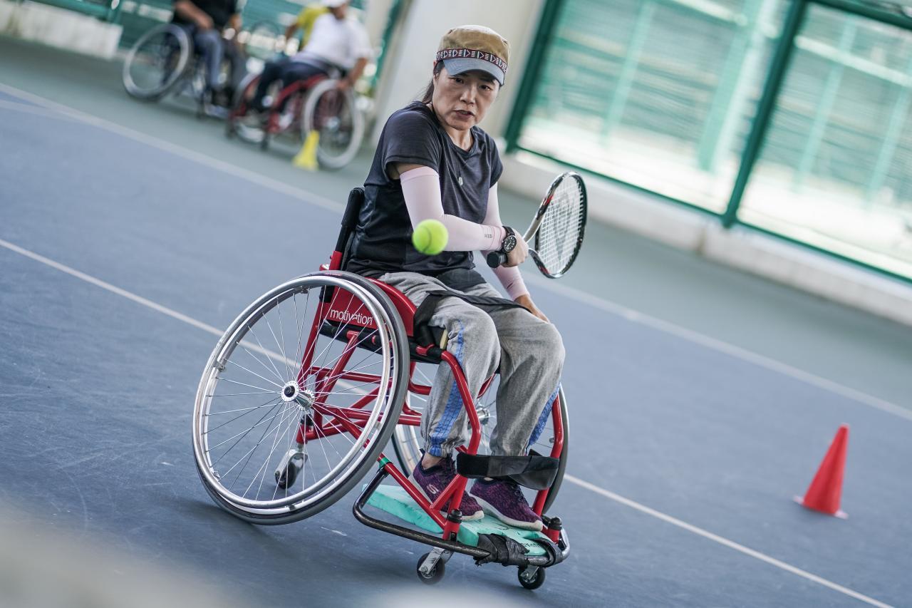 女性輪椅網球運動員用球拍擊打網球