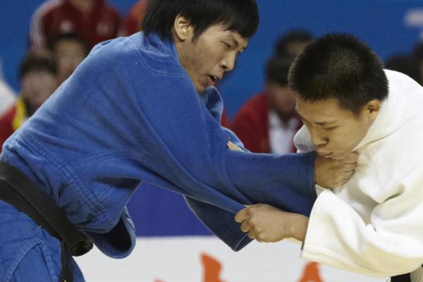 一名穿藍色柔道服的選手與一名穿白色柔道服的選手正在進行柔道比賽